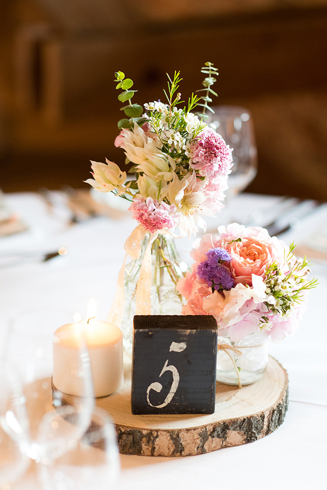 Tischdekoration mit Baumscheibe, Tischnummer und verschiedenen Blumenvasen